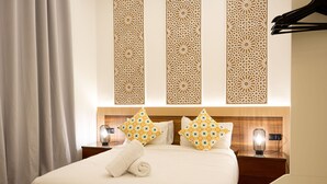 A neatly made bed with a rolled towel, a nightstand with a lamp, and decorative panels above the bed. - Casa Verdi with Terrace, 1 Bedroom, Living Room (Tanger)