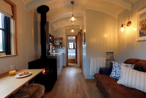 A cozy interior with a kitchen, dining area, and seating space. - Luxury Shepherds Hut with hot tub, firepit and gas barbeque (Anglesey)