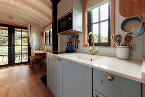 A kitchen with a large island, a microwave, and a sink. - Luxury Shepherds Hut with hot tub, firepit and gas barbeque (Anglesey)