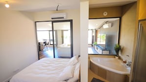 Ein Hotelzimmer mit einem Bett, einem Badezimmer mit einer Badewanne und einem großen Spiegel.