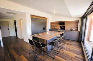 Une cuisine moderne dotée d’un îlot central, de planchers en bois foncé et offrant une vue sur l’extérieur.