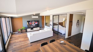 Ein modernes Wohnzimmer mit einem weißen Sofa, einem Holzes Esstisch und einem Flachbildfernseher.