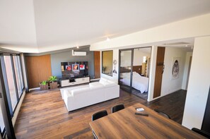 Un salon moderne avec un canapé blanc, une table à manger en bois et un téléviseur à écran plat.