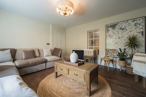 Ein Wohnzimmer mit einer Couch, einem Couchtisch, einem Sessel, einer Stehlampe und einer Wand mit einer Dekoration.
