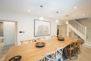 Ein Essbereich mit Holztisch, Stühlen, Pendelleuchten und einem gerahmten Kunstwerk an der Wand.