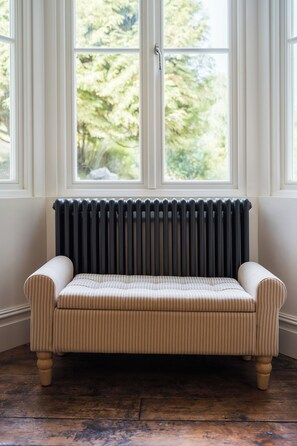 Ein gestreiftes Sofa in einem Zimmer mit Heizkörper und Blick auf Grünflächen.
