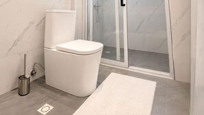 A modern bathroom with a toilet, a glass-enclosed shower, and a marble floor. - Bruce Palace Hotel (Ngleshi Amanfro)