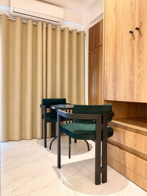 Ein Zimmer mit Esstisch und Stühlen, einem Holzschrank und beigen Vorhängen.