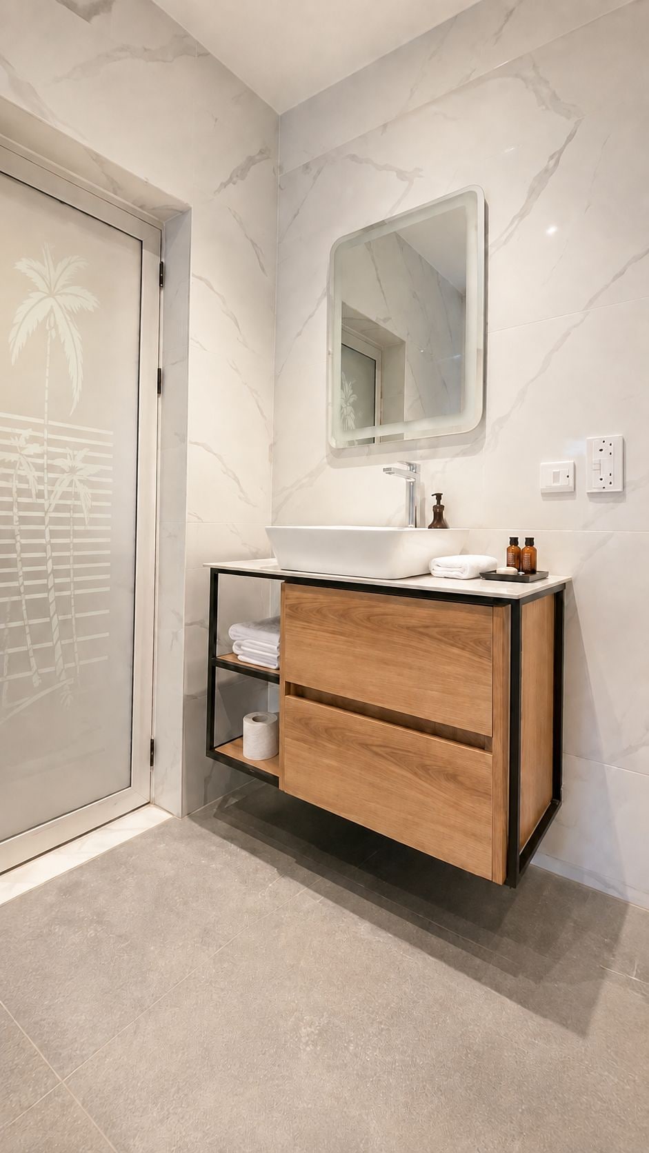 A modern bathroom with a marble wall, a wooden vanity, a mirror, and a toilet paper holder.