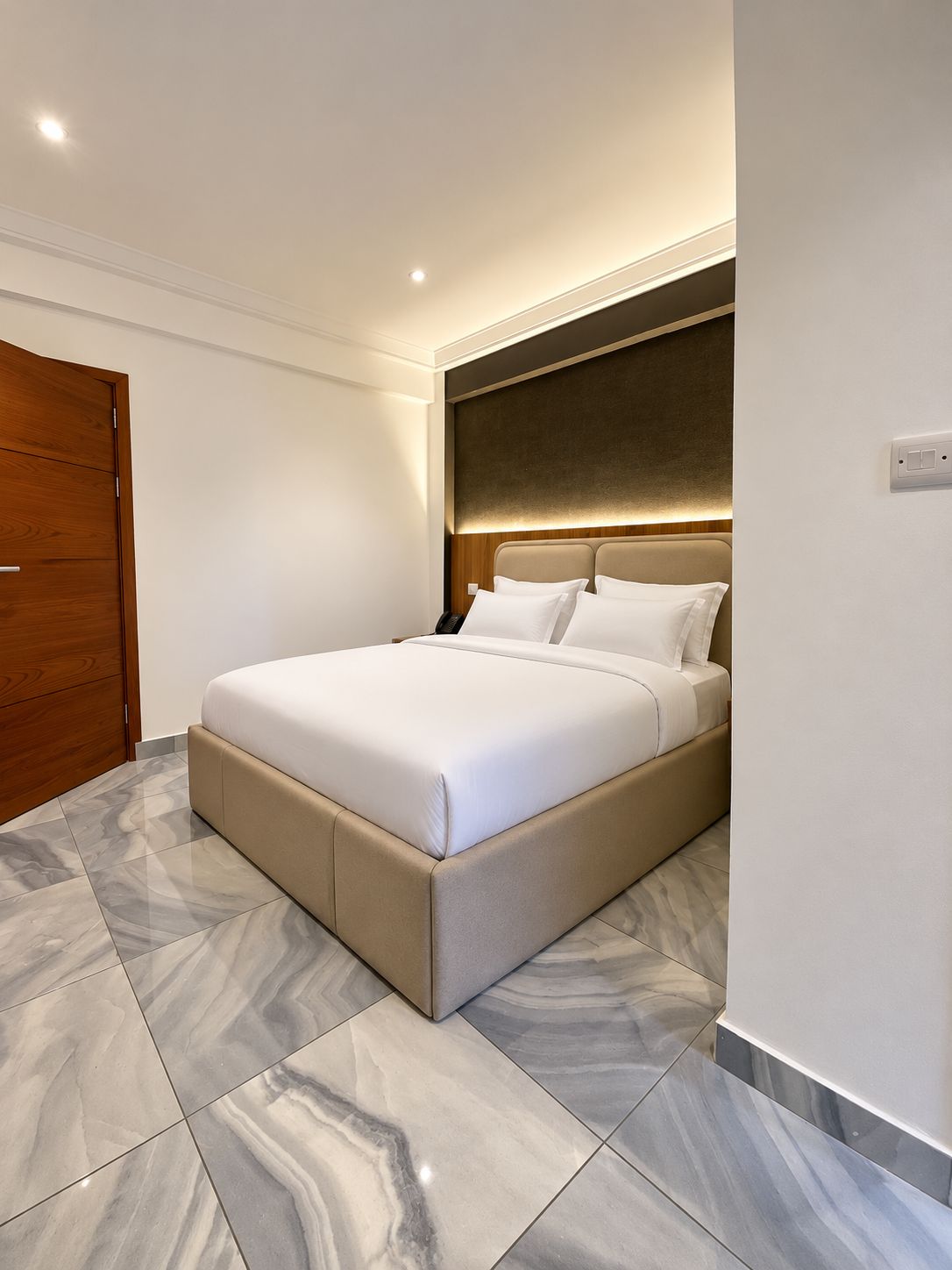Een moderne slaapkamer met een groot bed, een houten garderobe en marmeren vloeren.