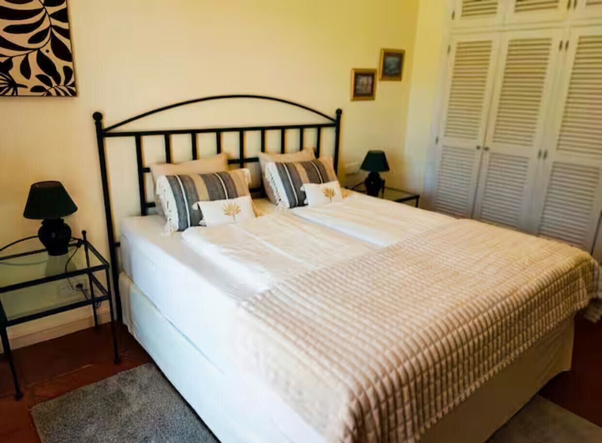 A bed with a headboard, two bedside tables, and a lamp on each side.