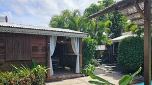 Une cabane en bois dotée d’un patio couvert, d’une piscine et d’une végétation tropicale.