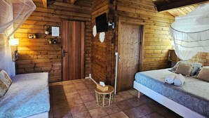 Una accogliente camera in una baita di legno con due letti, una ventola a soffitto e un tavolino con una scatola di fazzoletti.