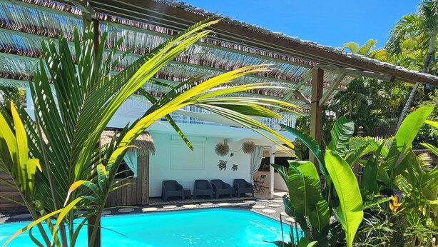 Area piscina con sedie a sdraio, piante in vaso e una struttura a pergola.