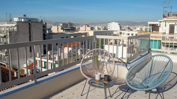 A balcony with a view of the city, two chairs, and a small table with a cup and saucer. - Studio with a view of the Acropolis, close to the metro and tourist attractions (Athina)