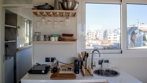 A modern kitchen with a built-in oven, a sink, and a window with a city view. - Studio with a view of the Acropolis, close to the metro and tourist attractions (Athina)