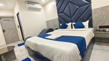 A modern bedroom with a bed, a bedside table, a blue rug, and a wall-mounted air conditioner.