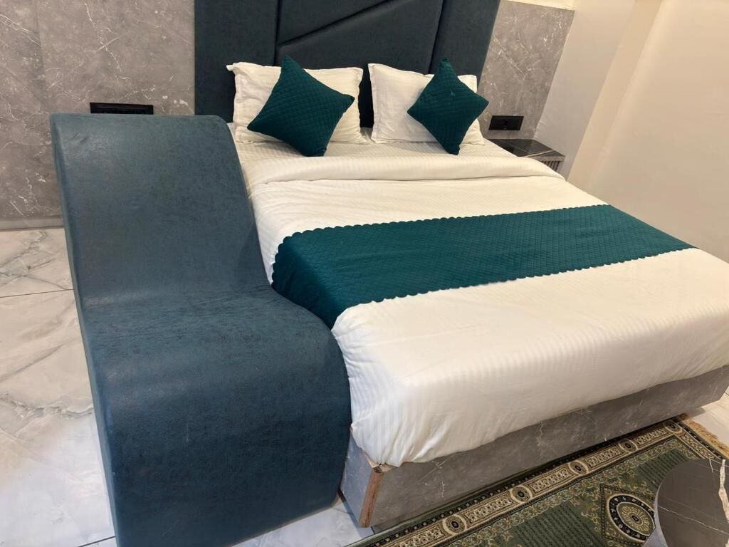 A bed with a headboard, a bench, and a patterned rug.
