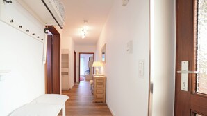 A hallway with a bench, a dresser, a lamp, and a door. - Hansastrasse Building, Apartment 1 (Scharbeutz)