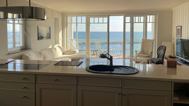 A modern kitchen with a large island, a dining area with a view of the sea, and a cozy seating area with a sofa and chairs. - "Prinz Heinrich" Ocean View Villa - Molenblick Apartment (Sassnitz)