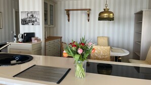 A modern kitchen with a built-in stove, a coffee machine, and a vase of flowers on the counter. - "Prinz Heinrich" Ocean View Villa - Molenblick Apartment (Sassnitz)