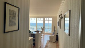A hallway with a view of the ocean, framed artwork on the walls, and a seating area with a view. - "Prinz Heinrich" Ocean View Villa - Molenblick Apartment (Sassnitz)