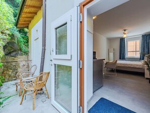 A room with a bed, a desk, and a chair, with a view of a garden and a stone wall outside. - Via Monte Brione by Interhome (Arco)