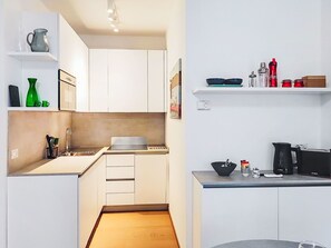 Una cocina moderna con armarios blancos, un lavamanos, una estufa y una cafetera.