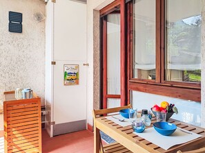 Um quarto com uma mesa de madeira, uma janela com vista, uma porta com um cartaz e um ar condicionado fixado na parede.
