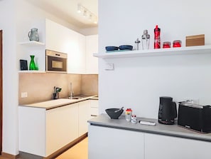 Eine moderne Küche mit weißen Schränken, einer Mikrowelle, einem Spülbecken und verschiedenen Küchengeräten.