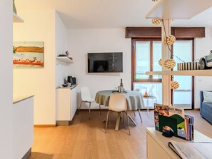 Un espacio moderno para vivir con comedor, televisión de pantalla plana y estantería.