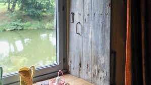 Een houten raam in rustieke stijl, met uitzicht op groen en een waterlichaam.