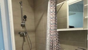 Un baño con ducha, lavamanos y espejo.