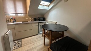Una cocina compacta con tragaluz, una pequeña mesa de comedor y una cama.