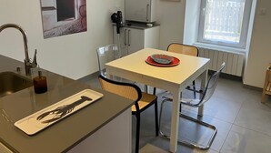 Eine kleine Küche mit Spüle, einem Esstisch mit Stühlen, einer Heizung und einem Fenster.