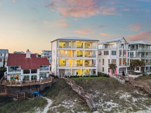 Ein mehrstöckiges Hotel direkt am Strand mit Balkonen, einer überdachten Terrasse und einem Sandstrand.