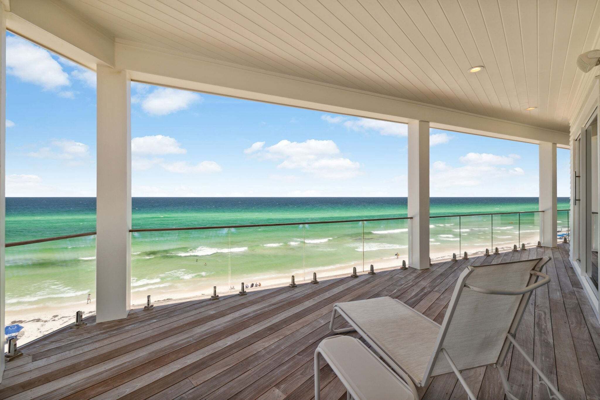 A covered wooden deck with a view of the beach and ocean.