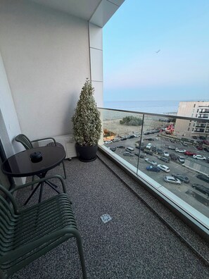 Ein Balkon mit Blick auf den Strand, einer Topfpflanze, einem Tisch und Stühlen.