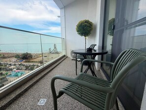 Ein Balkon mit Meerblick, ein kleiner Tisch mit Stühlen und ein Blumentopf.