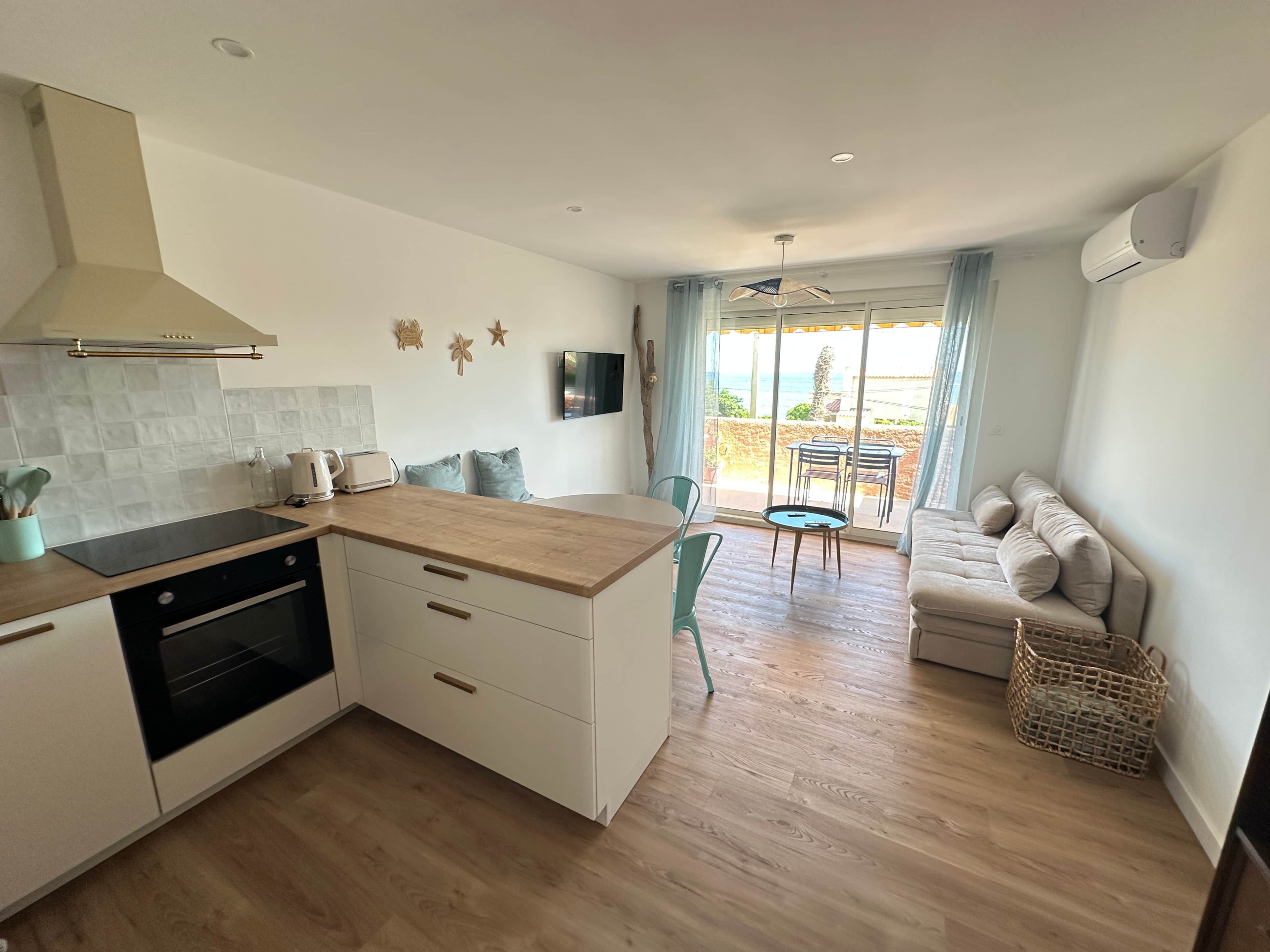 Eine moderne Küche mit Backofen, ein Essbereich mit Tisch und Stühlen sowie eine Sitzecke mit Sofa.