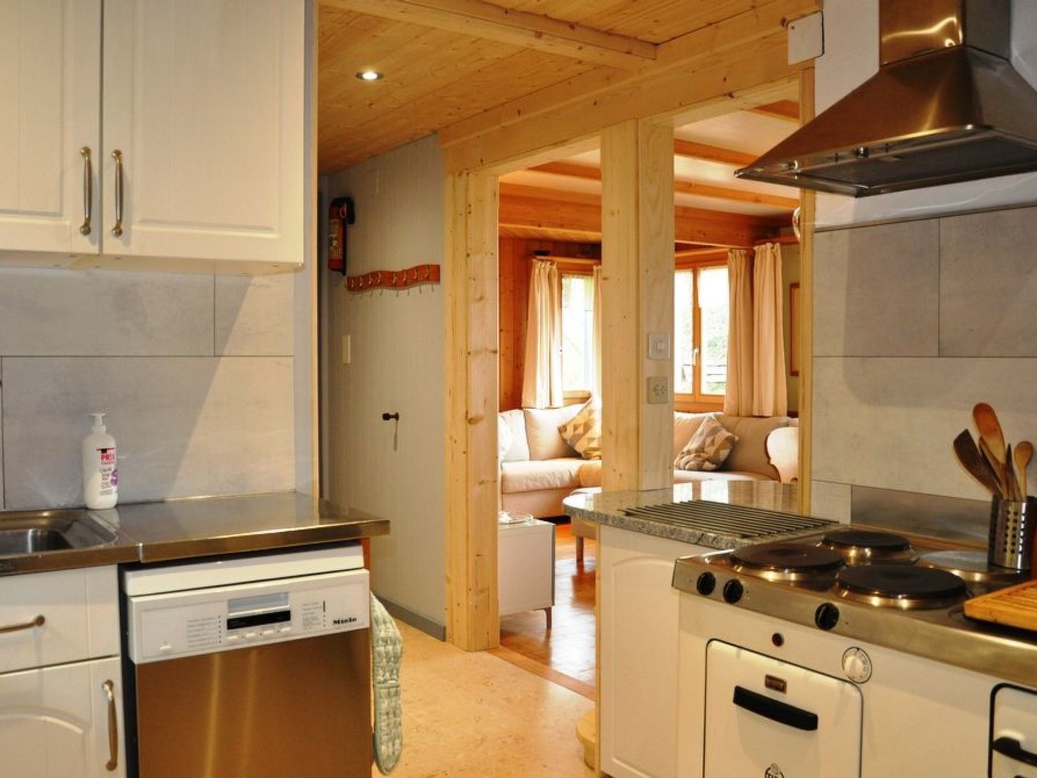 Una cocina con electrodomésticos modernos, un comedor con sofá y vista hacia una sala de estar.