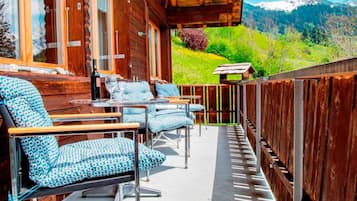 Une terrasse en bois avec des sièges extérieurs et une vue sur un paysage montagneux.