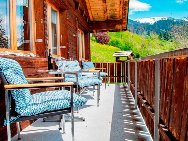 A wooden deck with outdoor seating and a view of a mountainous landscape.