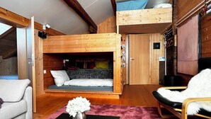 Een loft-stijl kamer met een stapelbed, een bank, een stoel en een tafel met een vaas.