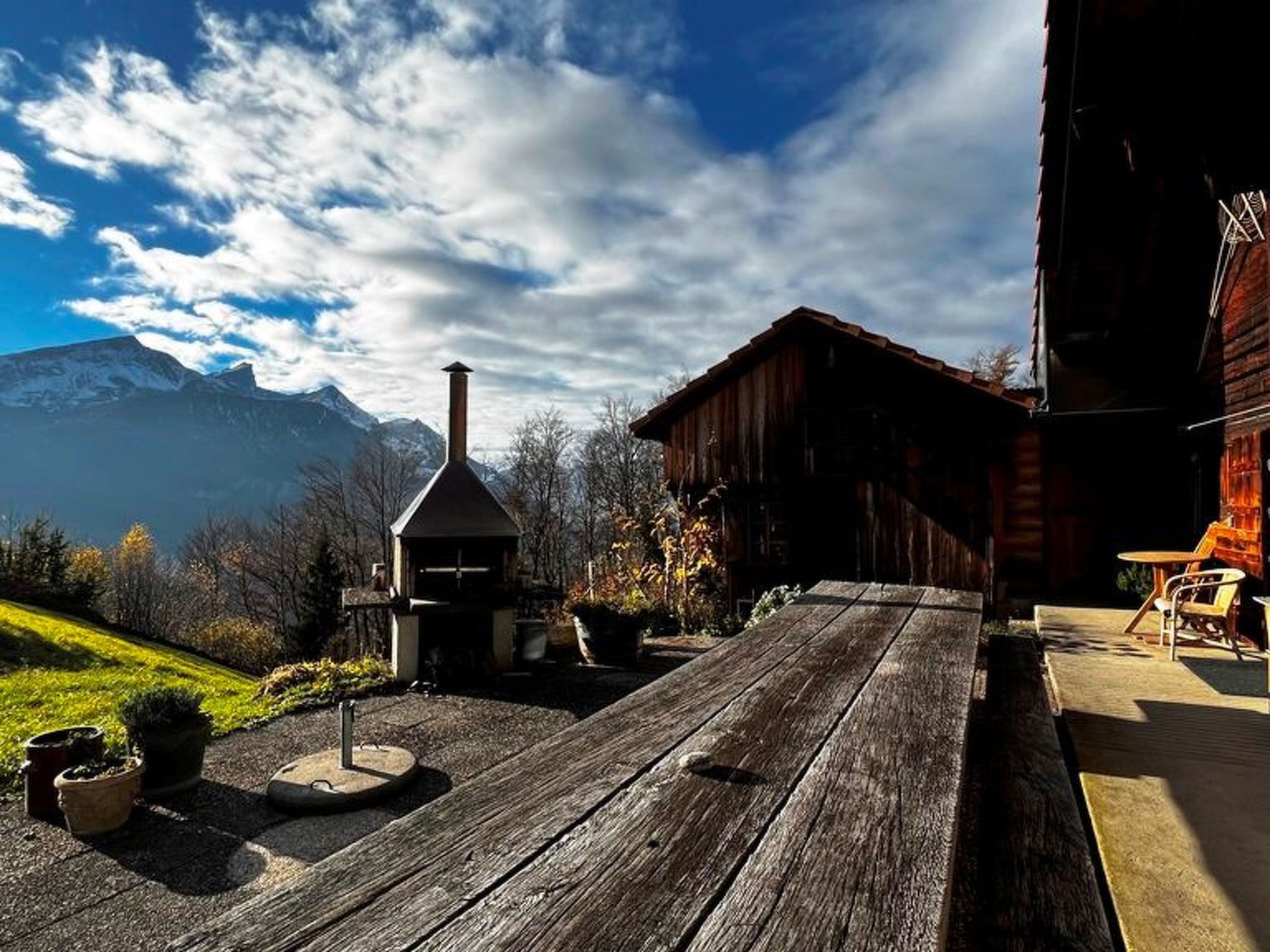 A wooden deck with a rustic building, a chimney, and a mountain view.