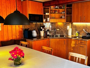 A kitchen with wooden cabinets, a microwave, a coffee maker, and a sink. - HasliRent, Lindeli, (Hasliberg Reuti), by Interhome (Hasliberg)