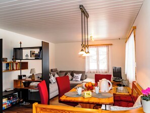 Ein modernes Wohnzimmer mit Essbereich, einer Couch, einem Fernseher und einem Bücherregal.