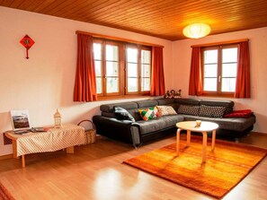 Ein Wohnzimmer mit einer Couch, einem kleinen Tisch, einem Teppich und einem Fenster mit Vorhängen.