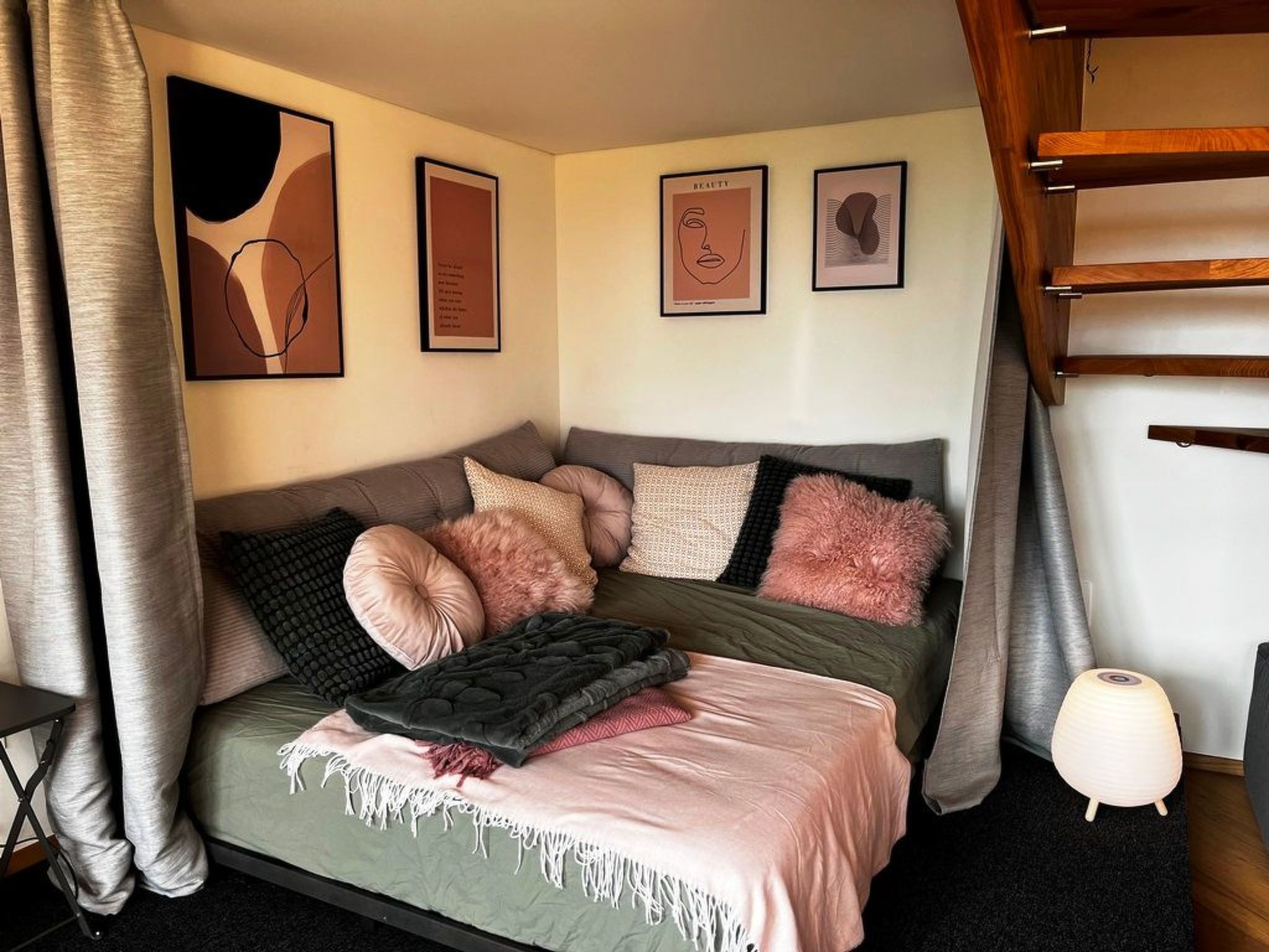 Une chambre à coucher avec un lit, des oreillers, une couverture et des œuvres d’art murales.