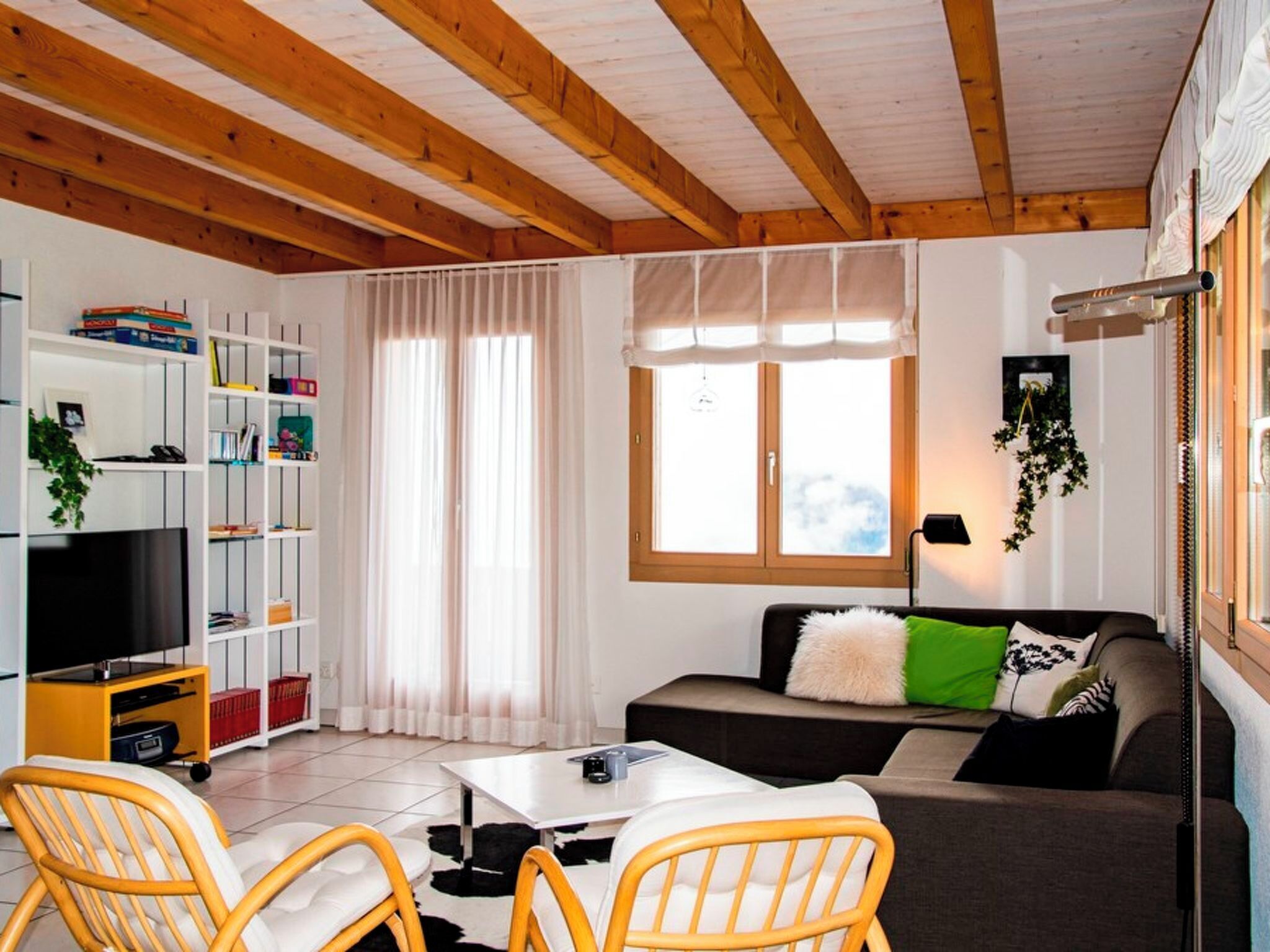 Un salon comprenant un téléviseur, un canapé, des fauteuils, une table basse et une bibliothèque.